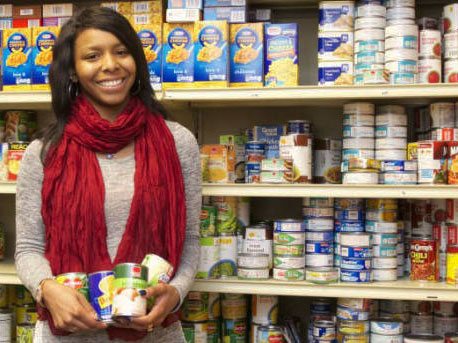 A woman standing in front of shelves stocked with food.