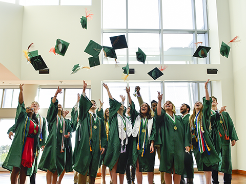 Group of students throwing their graduation caps into the air.