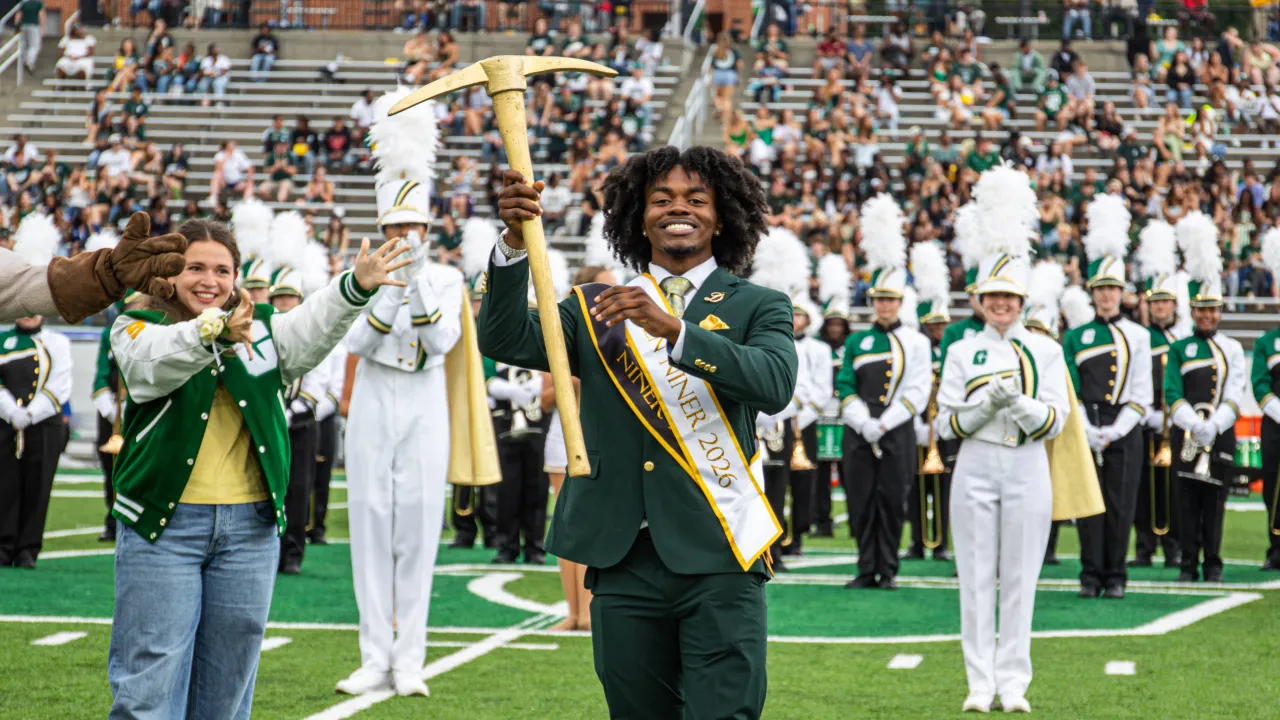Dacien Montford smiling with the Golden Pickaxe after winning the Golden Niner, with former winner Abby Grace Bare in the background