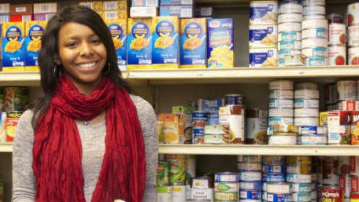 A woman standing in front of shelves stocked with food.