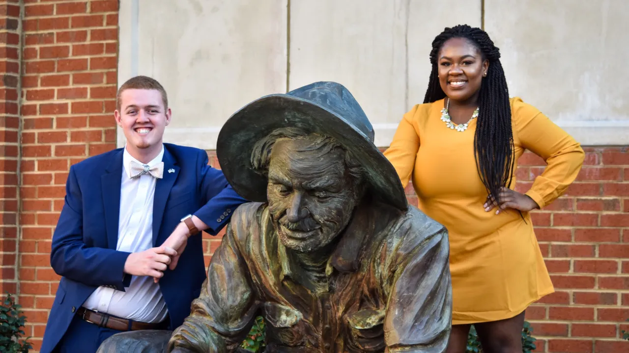 Niayai Lavien and Chandler Crean standing next to the Norm the Niner statue.