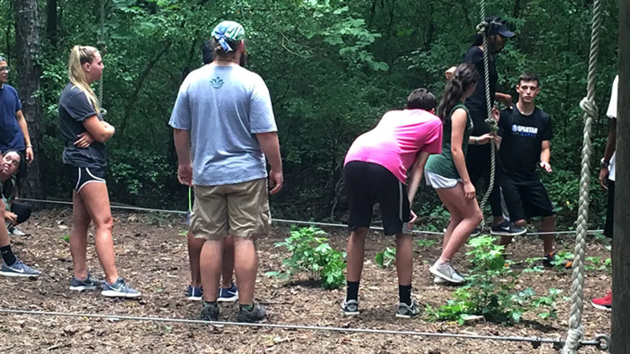 Group of students participating in a low ropes team building exercise.