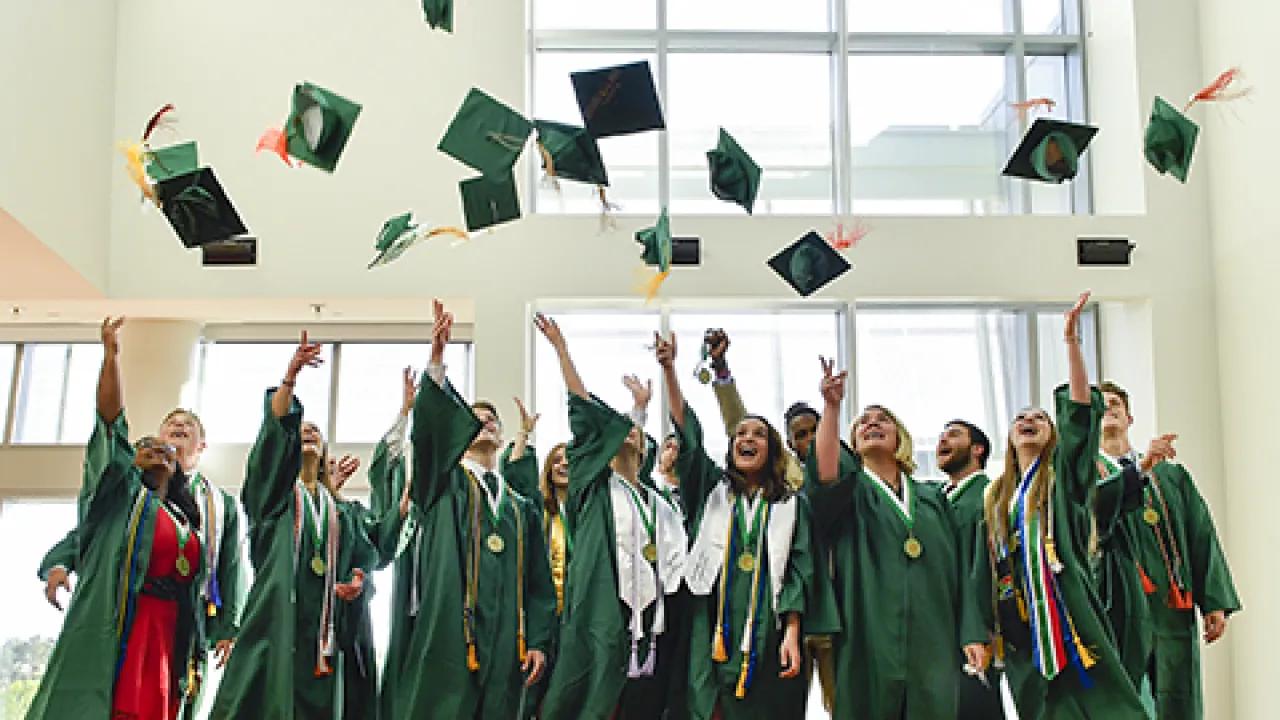 Group of students throwing their graduation caps into the air.