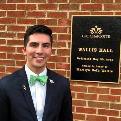 Estevan Torres standing by the sign for Wallis Hall.
