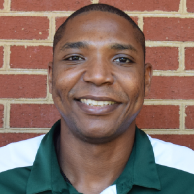 Chris Washington smiling in front of a brick wall
