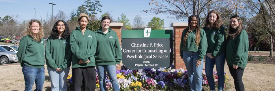 Student peer leaders standing outside of the CAPS building next to the building's sign