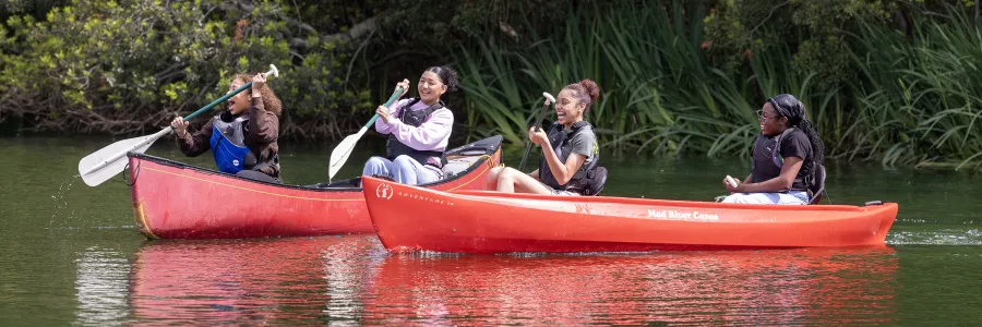 Four students in canoes at Light Up the Lake event
