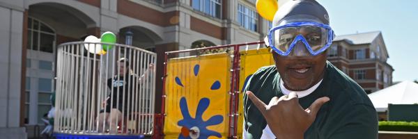 Vice Chancellor Bailey promoting Niner Nation Gives at dunk tank on outdoor plaza