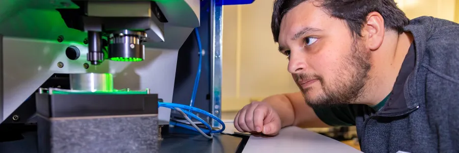 Jorian Khan looking at a machine used in metrology