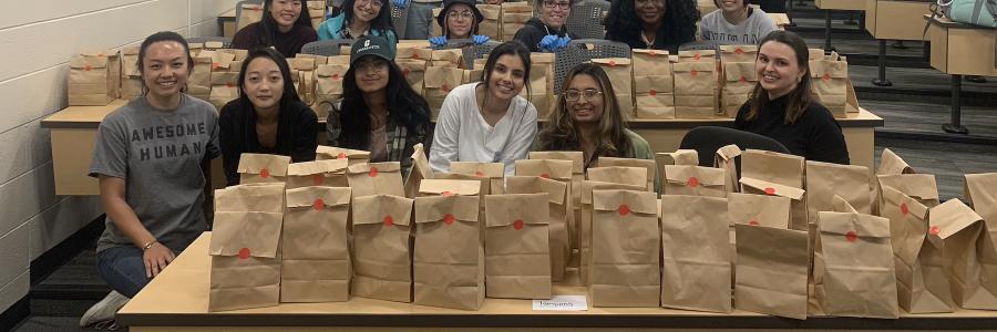 Members of AMWA with bags of menstrual products to hand out to students.