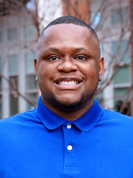 Benjamin Moten smiling outside in a blue polo
