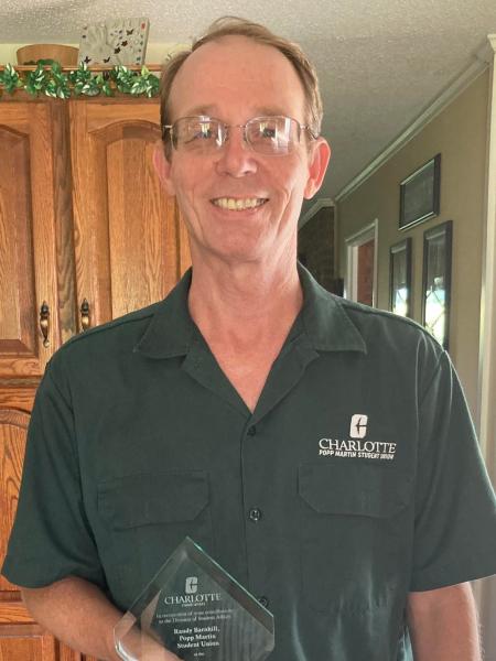 Randy Barnhill smiling while holding his Above and Beyond Award