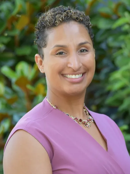 Denise Balfour Simpson smiling in front of greenery