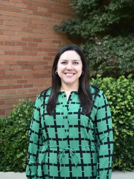 Katie Russo smiling in a green and black dress outside