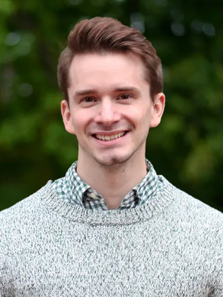 Michael Maksymowski smiling in a gray sweater outside