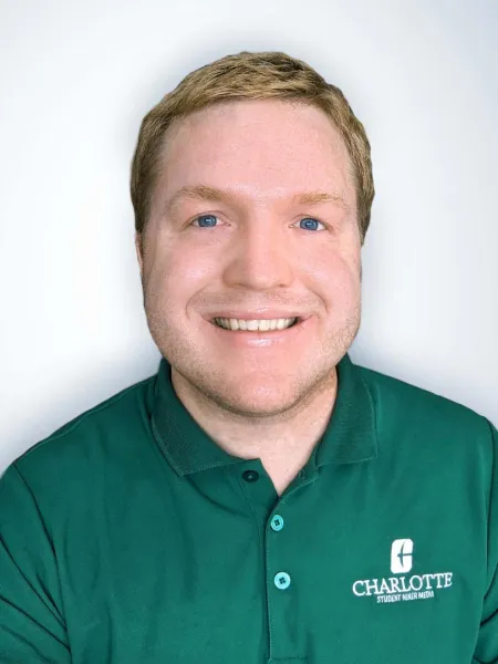 Joshua Wood smiling with a green UNC Charlotte polo