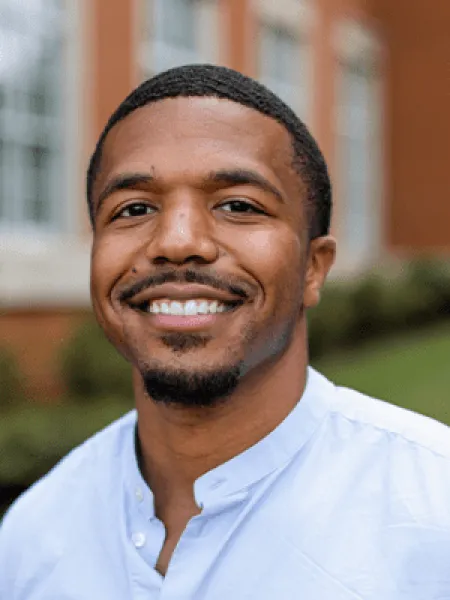 Joshua similing outside in a button-up shirt