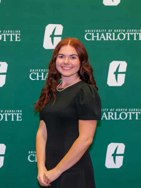 Madison File smiling in front of a UNC Charlotte backdrop