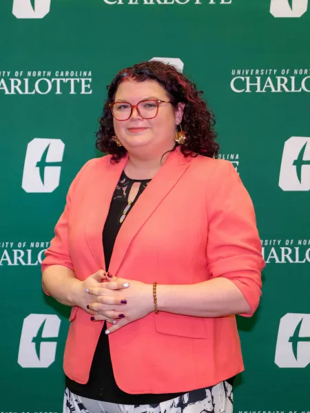 Megan Mitchem smiling in front of the UNC Charlotte backdrop