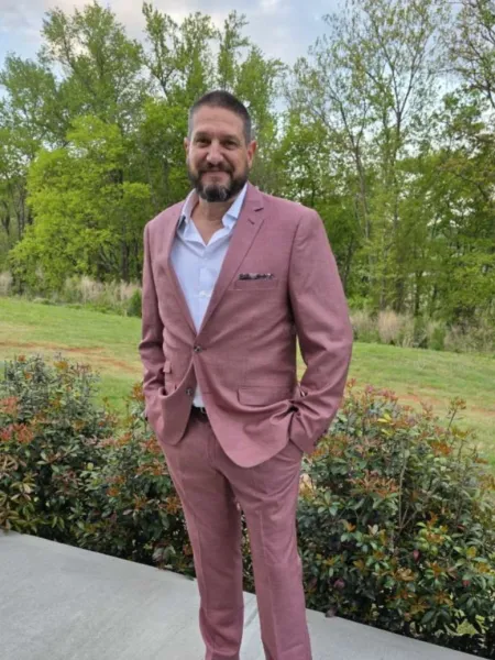 Steven Begley in a salmon-colored suit posing outside