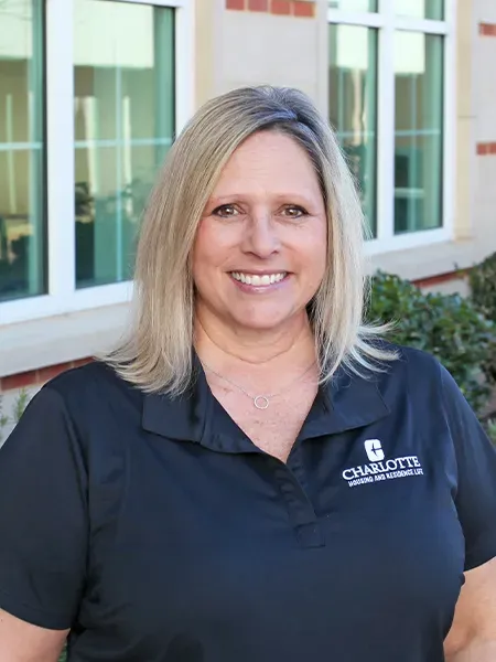 Wendy Moore smiling in front of a building in a black Housing and Residence Life polo shirt