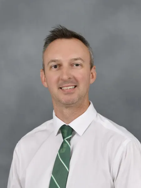 Adam Burden smiling in a green tie