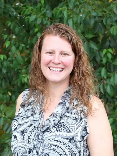 Stephanie Rewitzer smiling in front of greenery