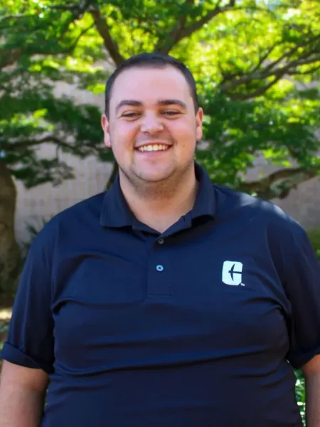 Lance Bumgardner smiling in a black polo with the All In C