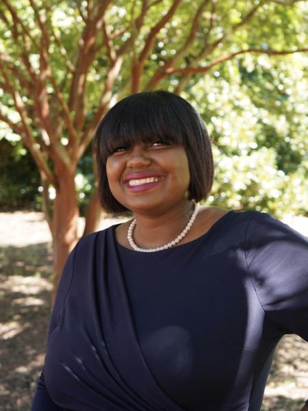 Janay Crosland smiling while standing under a tree