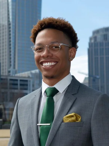 Shaun Coleman smiling in front of a city with a green tie.
