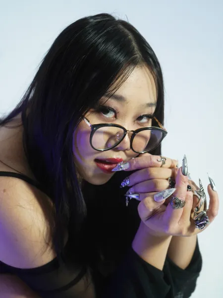 Sophia Park looking from the side with her creative nail designs on display on her hand