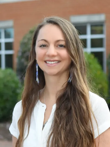 Katie Tomer in a white dress smiling outside