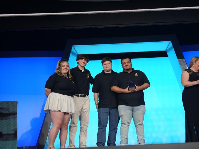 Niner Esports officers on stage winning the Club Program of the Year trophy.