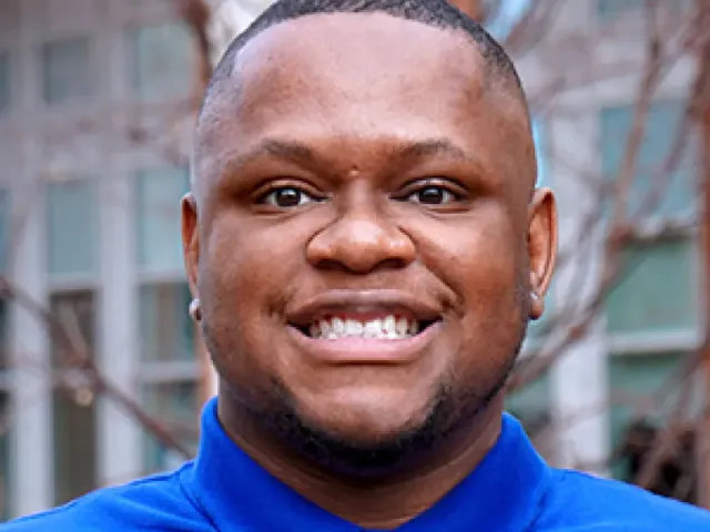 Benjamin Moten smiling outside in a blue polo