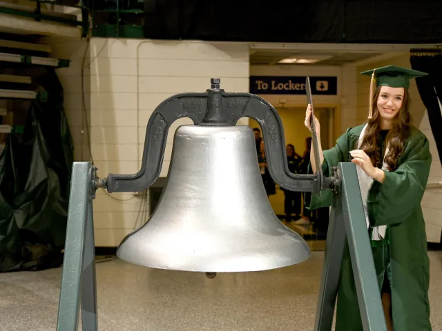 A former Charlotte student ringing the bell for commencement