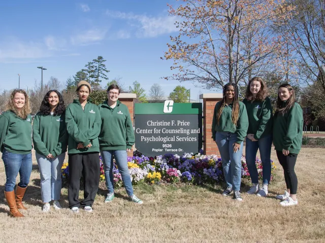 Student peer leaders standing outside of the CAPS building next to the building's sign