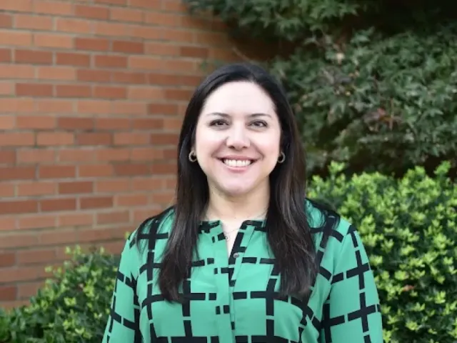 Katie Russo smiling in a green and black dress outside