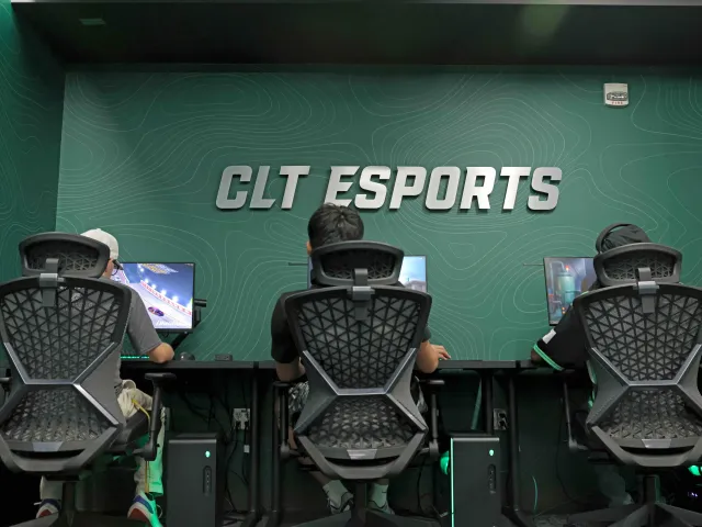 The backs of three students sitting in chairs in the Charlotte Esports Arena