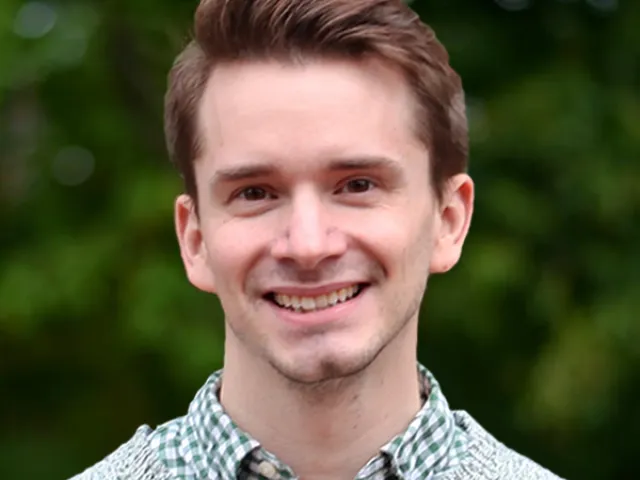 Michael Maksymowski smiling in a gray sweater outside