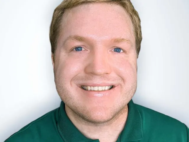 Joshua Wood smiling with a green UNC Charlotte polo