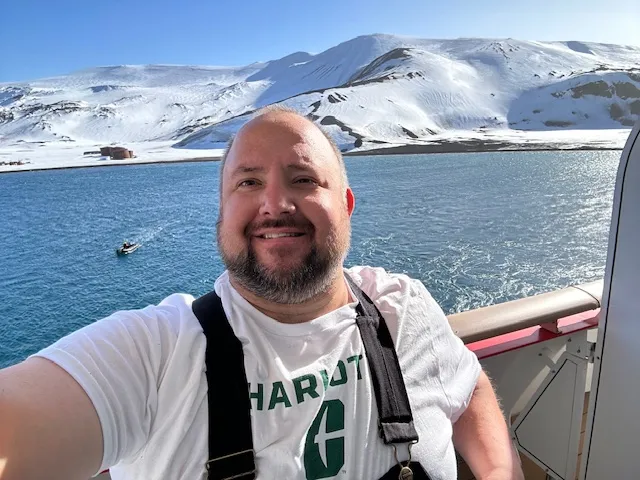 Jordan Słomiany smiling in a UNC Charlotte shirt while in Antarctica