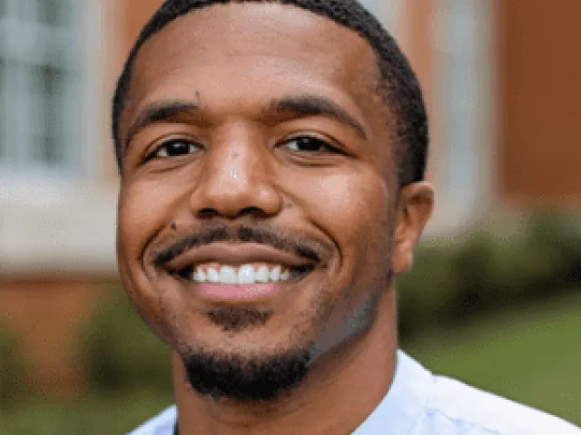 Joshua similing outside in a button-up shirt