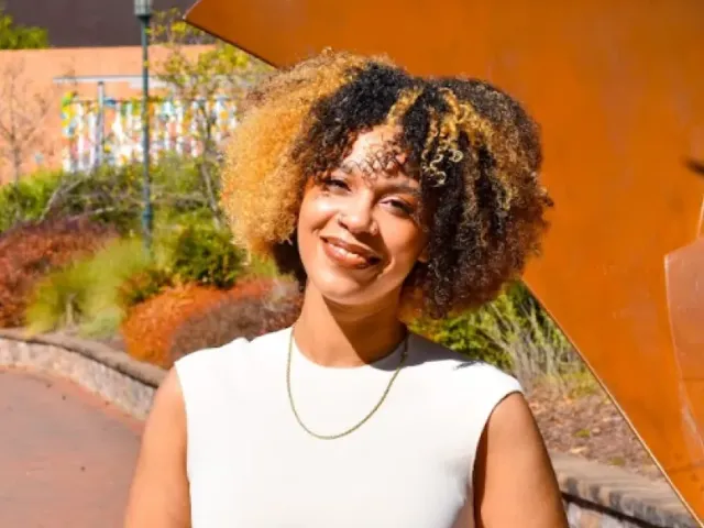 Shayauna Newsom smiling in a white top outside