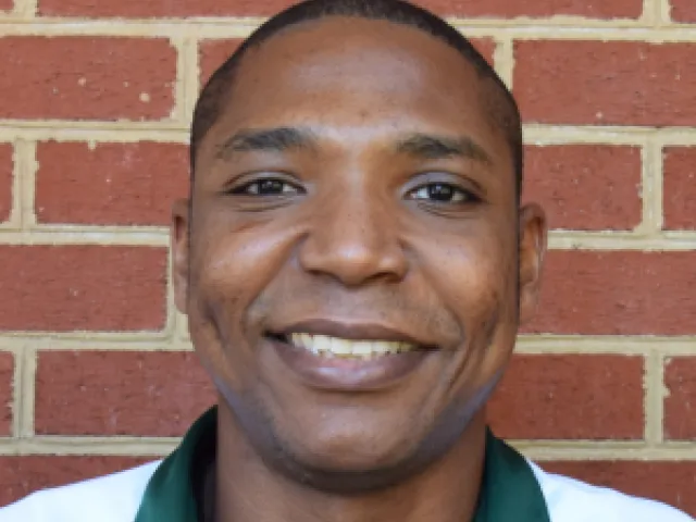 Chris Washington smiling in front of a brick wall