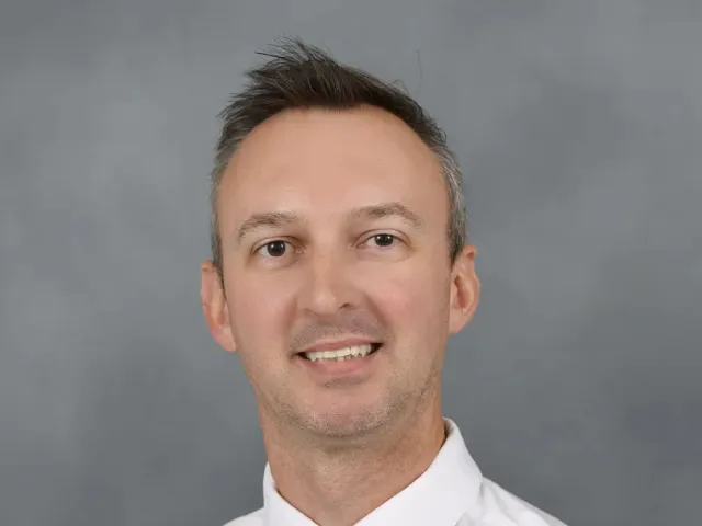 Adam Burden smiling in a green tie