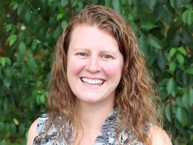 Stephanie Rewitzer smiling in front of greenery