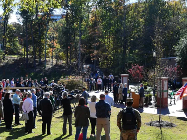 A crowd standing in Veterans Park for a service.