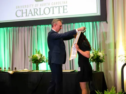 Adam Burden putting a sash on a student at the University Honors and Awards