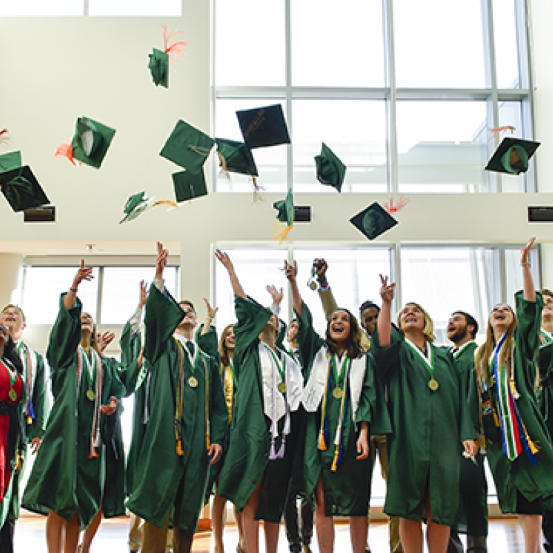 Group of students throwing their graduation caps into the air.