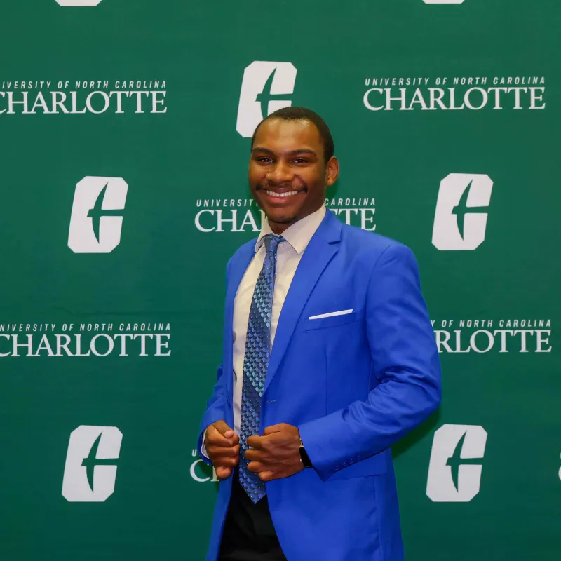 Brandon Pulliam smiling in front of the UNC Charlotte backdrop